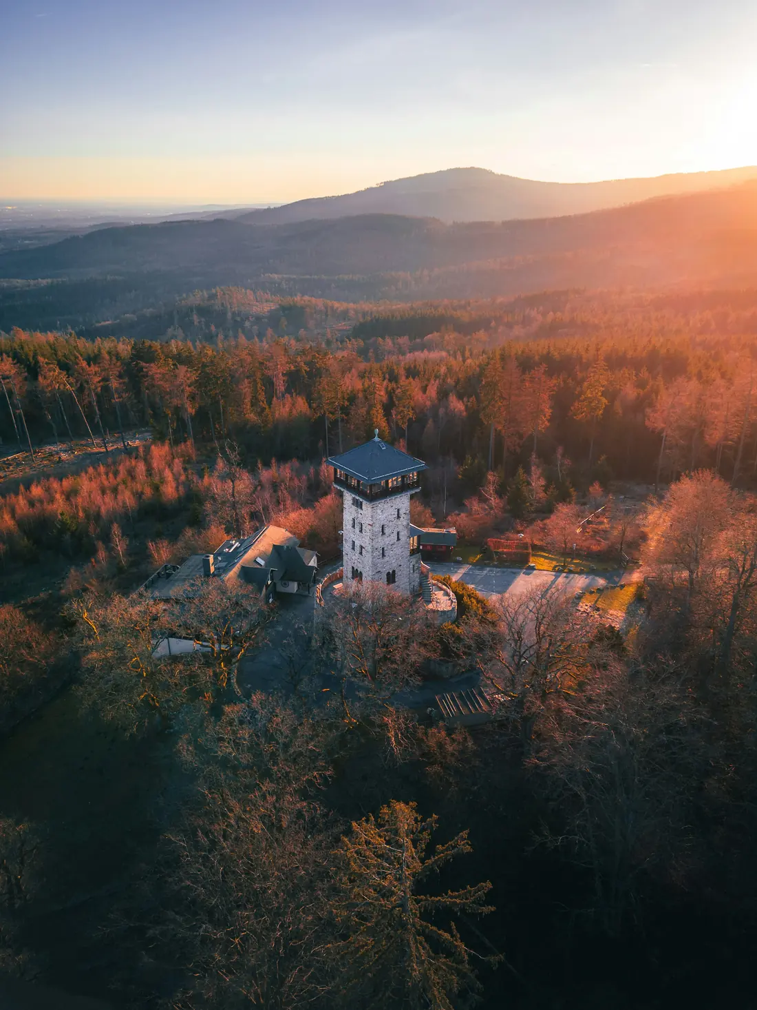Aerial view of a tower in a forest at sunset