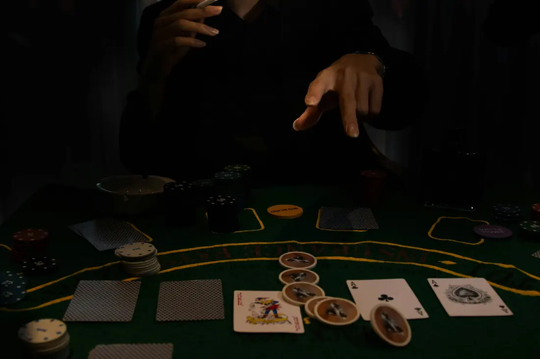 A player’s hand with cards and chips at a dark poker table