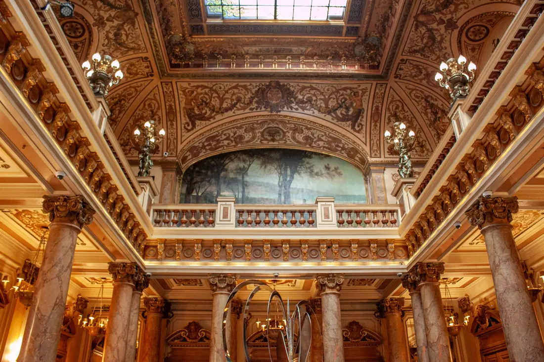 An ornate interior with columns, a balcony and a painted ceiling
